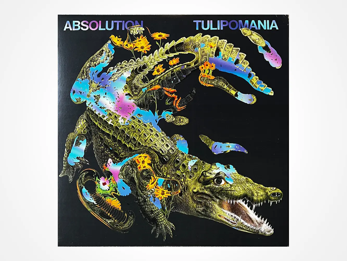A surreal illustration of a crocodile with colorful, abstract, paint-like splashes across its body on a black background. The words ABSOLUTION and TULIPOMANIA appear at the top in bold letters.