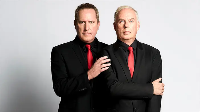 Two men in black suits with red ties stand against a plain light background, evoking a polished look ideal for a Home Template. One man rests his hand on the other’s shoulder as both look directly at the camera with neutral expressions.